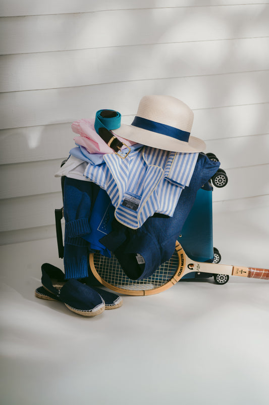 Bundle of summer sporting clothes with tennis racket against white wooden wall