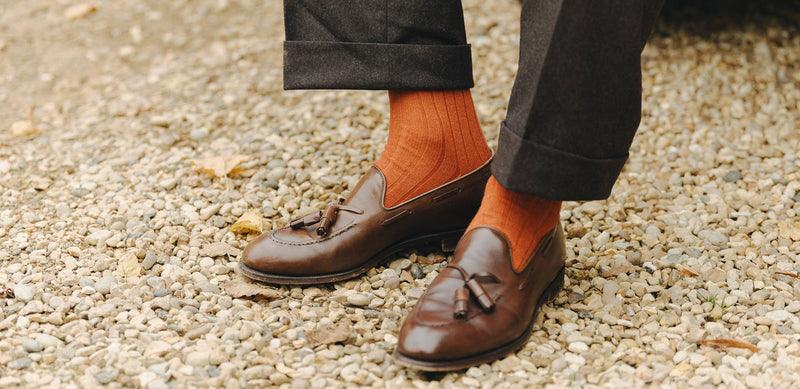Outdoor image of man wearing orange socks on gravel