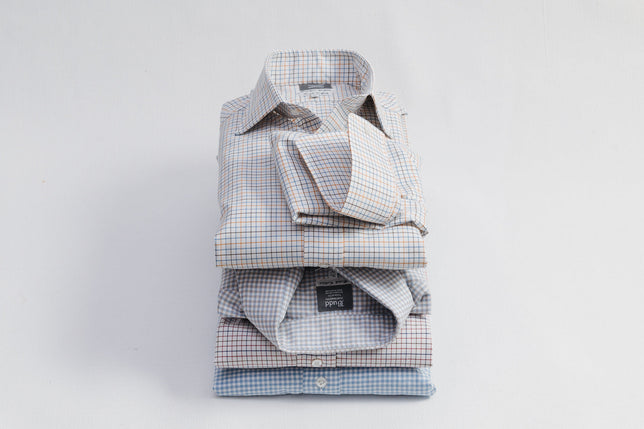 Stack of checked shirts piled up on plain background