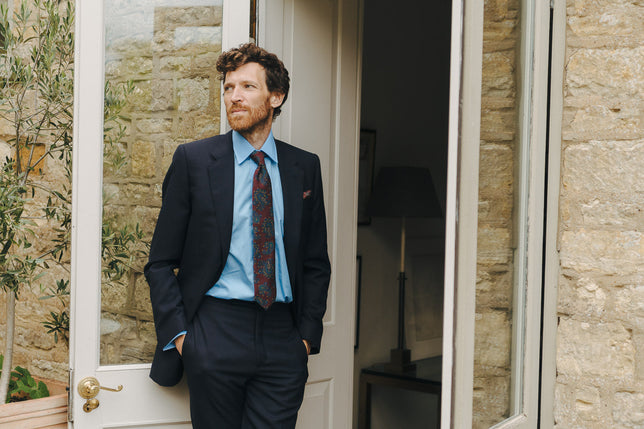 Model stood in doorway wearing suit and shirt and tie