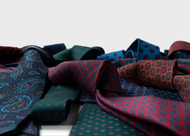 Collection of patterned ties in various colors on a light gray background