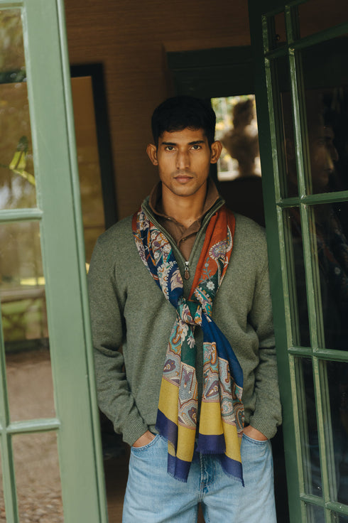 Man wearing a patterned scarf standing in front of a door.