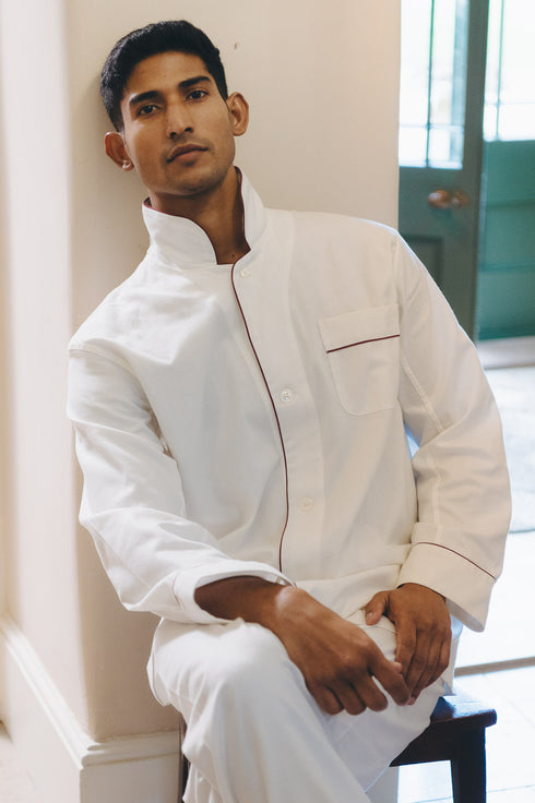 Male model sat against wall wearing white pyjama set