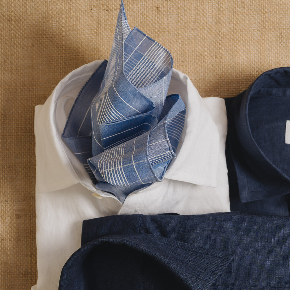 Folded navy shirt with a blue patterned pocket square on a beige surface