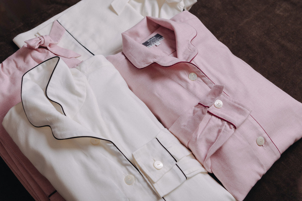 Womens pyjama sets in pink and cream laid on brown pain background