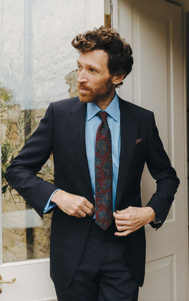 Man in a suit with a floral tie standing indoors