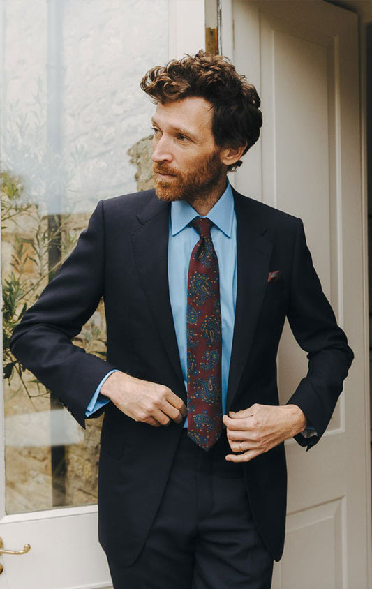 Man in a suit standing in a doorway with a stone wall background