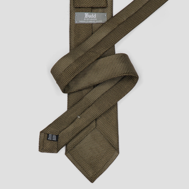 An olive green textured necktie with a woven pattern, neatly folded and displayed on a light gray background. The brand name 'Budd' is visible on the inner neck label.