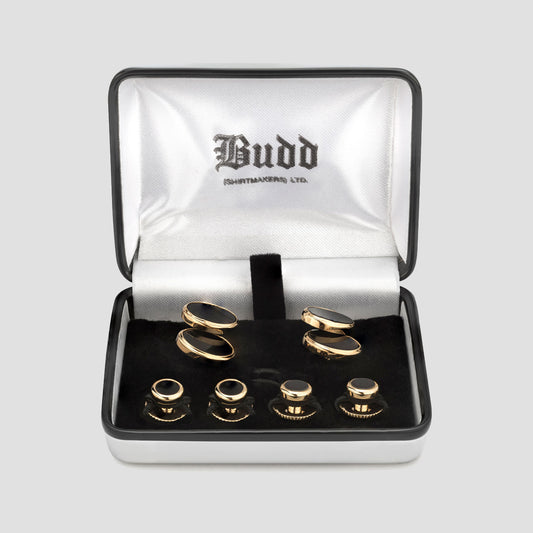A set of gold cufflinks and matching cufflinks in a black presentation box with a silver satin interior. The inside lid features the brand name 'Budd Cufflinks Ltd.