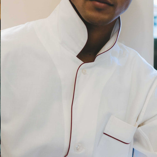 White pyjamas with red piping worn by a male