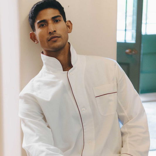 Man wearing a white pyjama set with red accents in a kitchen setting