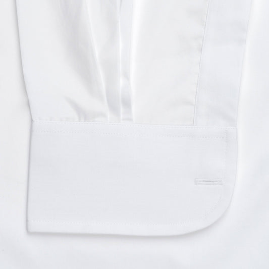 Close-up of a white long-sleeve dress shirt showing the pleated upper sleeve and a folded cuff with a single-button placket.