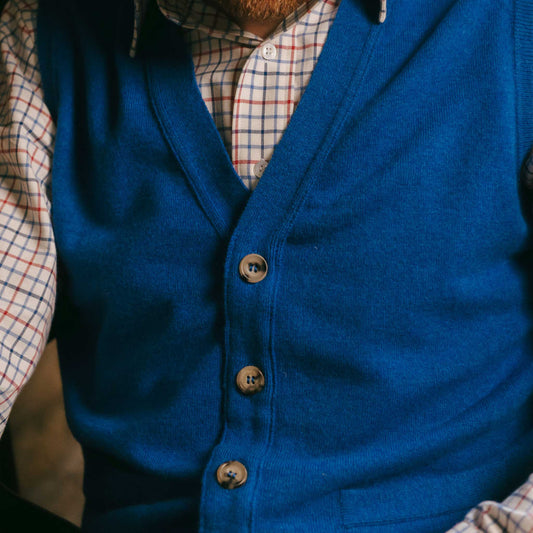 Blue cardigan with buttons worn over a plaid shirt.