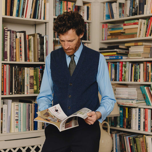 Man reading a book in a library filled with books