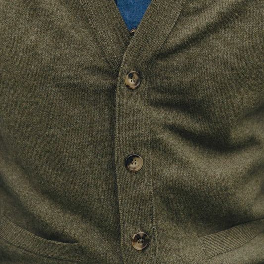 Close-up of a green cardigan with buttons on a plain background