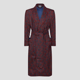 A long wrap robe with a red and navy paisley pattern, featuring a shawl collar, waist tie, and front pockets, displayed on a neutral light gray background.