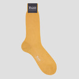 A single mustard yellow dress sock with a black brand tag at the cuff reading 'Budd Shirtmakers' and a small white logo near the foot, shown on a light gray background.
