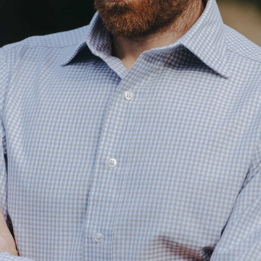 Close-up of a person wearing a blue checkered shirt with a blurred background