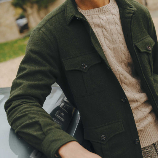 Detail shot of man wearing green safari jacket and beige cable knit jumper