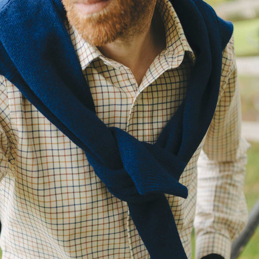 Man wearing a blue scarf over a plaid shirt outdoors
