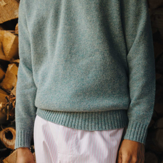 Person wearing a teal sweater with a blurred background