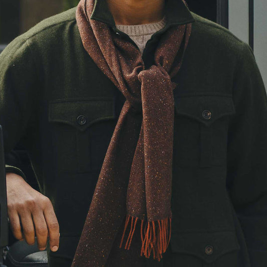 Person wearing a dark green jacket and brown scarf with a blurred background