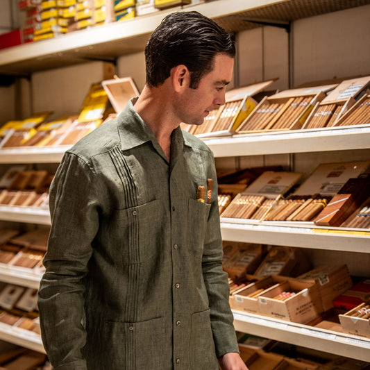 Man in a green shirt standing in front of a shelf displaying various items
