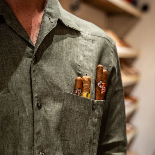 Person wearing a green shirt with cigars in the pocket, blurred background