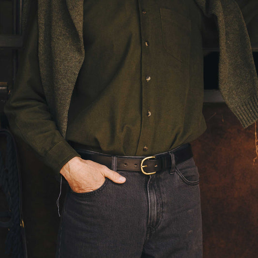 Person wearing a dark green shirt and black jeans with a blurred background