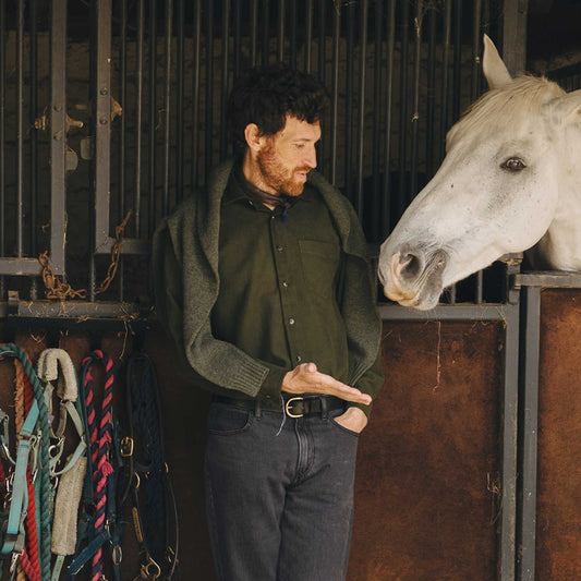 Man standing next to a white horse in a stable