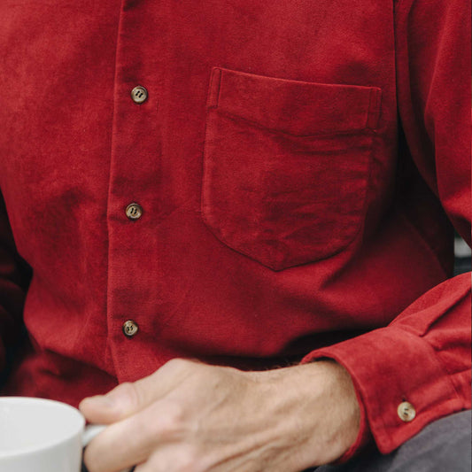 Close-up of a person wearing a red shirt holding a white mug.