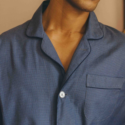 Close-up of a person wearing a blue checkered pyjama with a collar.