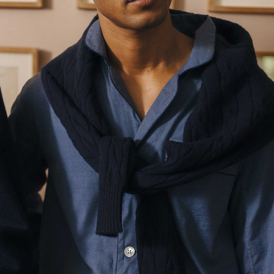 Person wearing a dark blue sweater over a light blue pyjama shirt with a blurred background