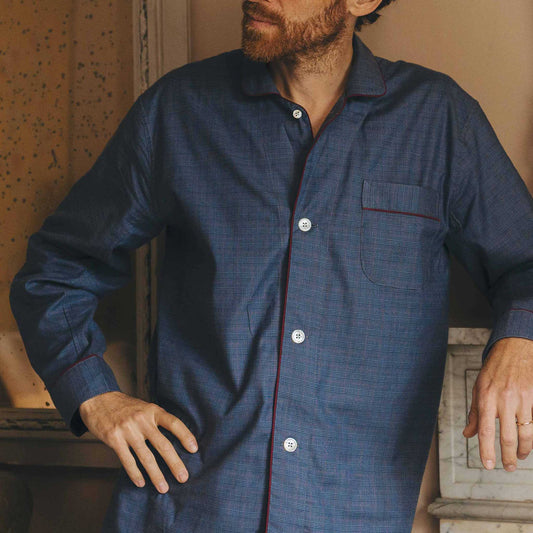 Man wearing a blue button-up pyjama shirt with a wooden background