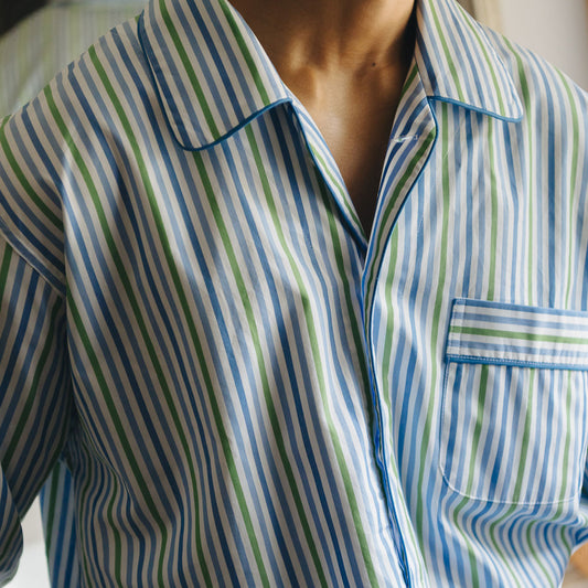 Close-up of a person wearing a striped pajama shirt with green, blue, and white colors.