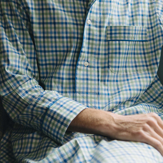 Man in a blue checked nightshirt sitting by a window