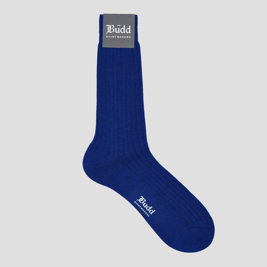 A single royal blue ribbed crew sock with white 'Budd Shirtmakers' branding, shown against a light gray background.
