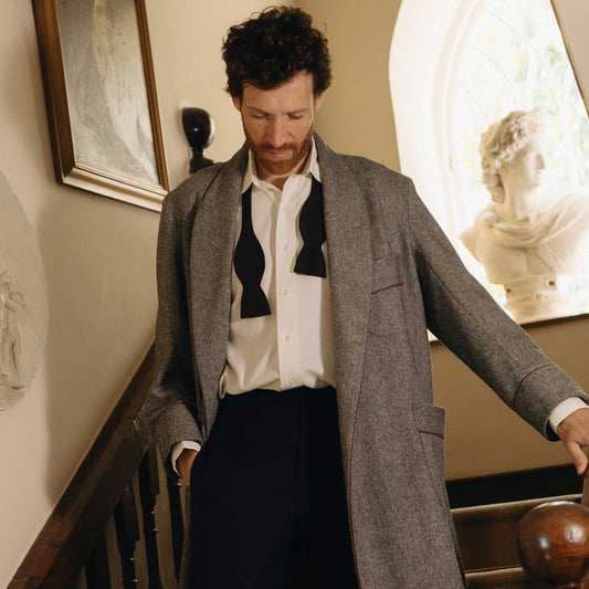 Male model stood on stairs wearing a grey herringbone tweed dressing gown