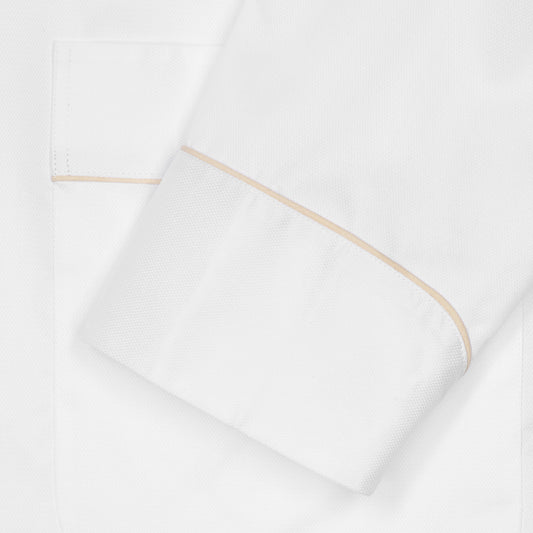 A close-up of a white textured fabric cuff with a thin beige piping detail, folded neatly.