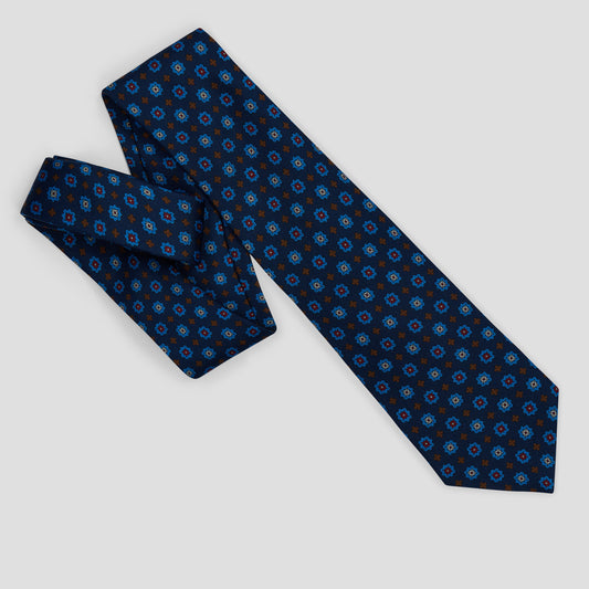 Navy madder silk tie featuring a repeating sky blue, burgundy, and burnt orange medallion print with an 8.5 cm blade.