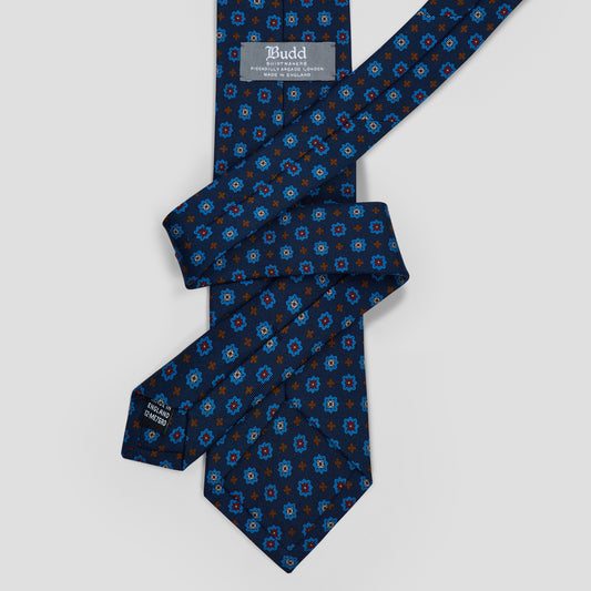 Navy madder silk tie featuring a sky blue, burgundy, and burnt orange medallion print, handcrafted in England.