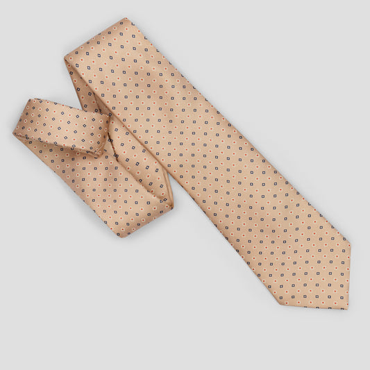 A peach-colored silk necktie with a small repeating geometric pattern of dark blue squares and dots, shown in a folded and tied presentation on a light gray background.