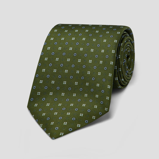 Olive green silk tie featuring navy and pale blue geometric floral dot medallions, hand-made in England with an 8.5cm blade.