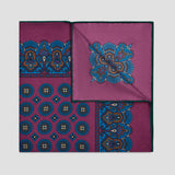 A folded silk pocket square with a magenta-purple base, featuring blue and gold geometric and paisley patterns, displayed on a light gray background.