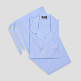 Sky blue pinstripe cotton poplin pyjamas with elegant white piping and a classic notched collar, folded neatly.