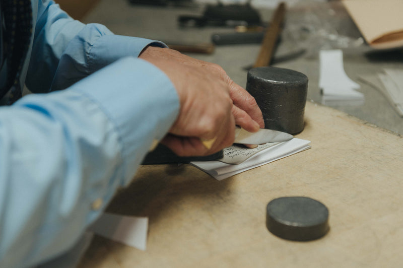 Person working with black cylindrical objects on a wooden surface