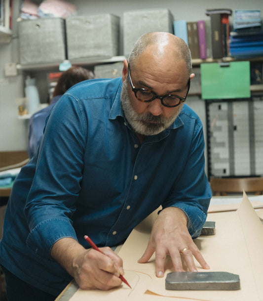 Head cutter measuring out and cutting a bespoke shirt in the cutting room