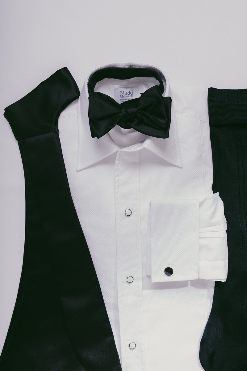 White dress shirt with black bow tie and sleeves on a light gray background