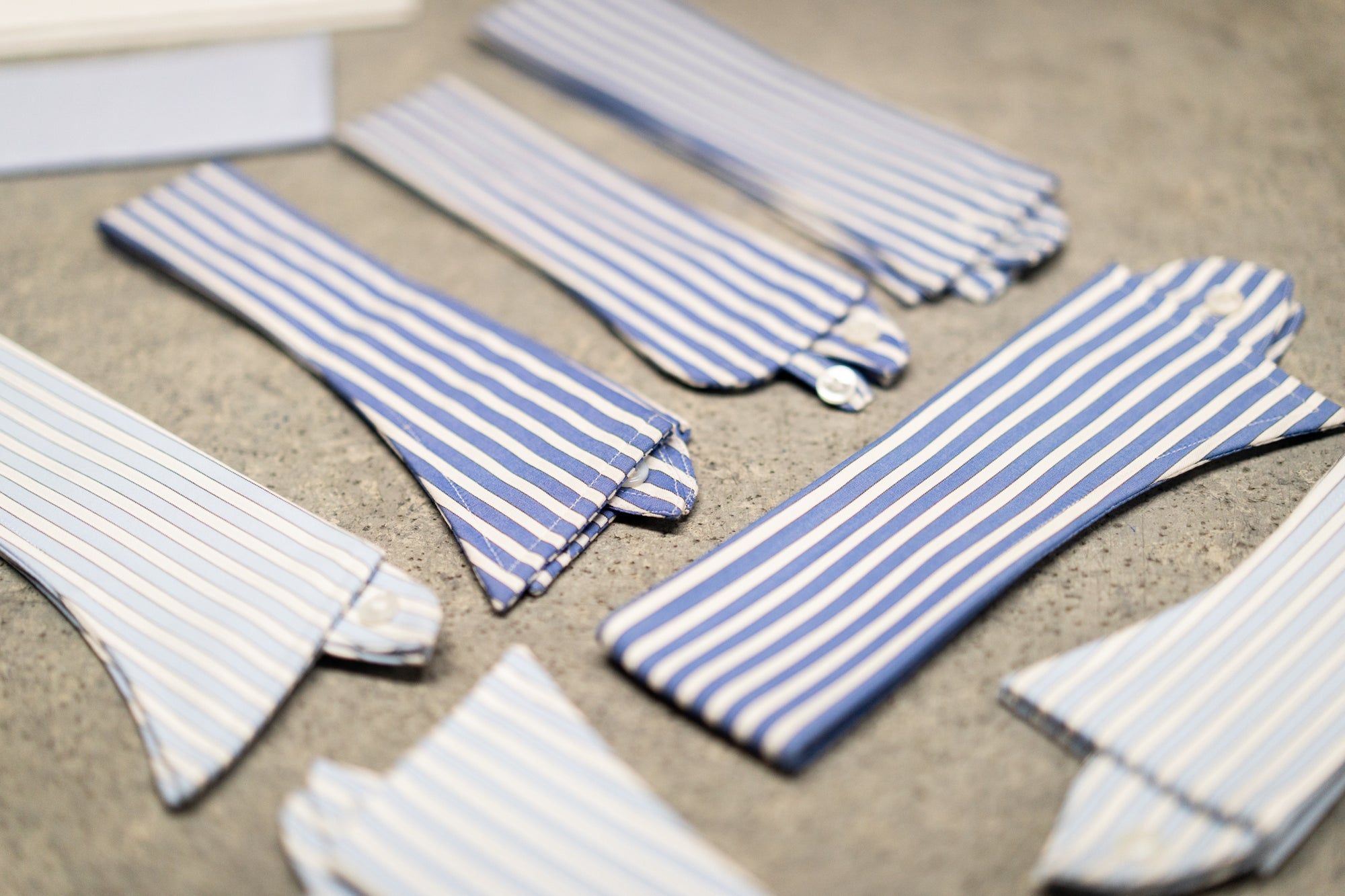 Set of blue and white striped shirt collars on a textured surface