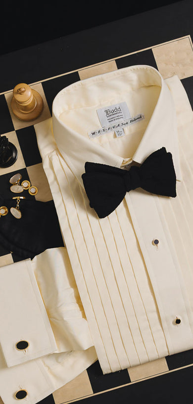Black tie shirt, bow tie and accessories laid on chess board with chess pieces